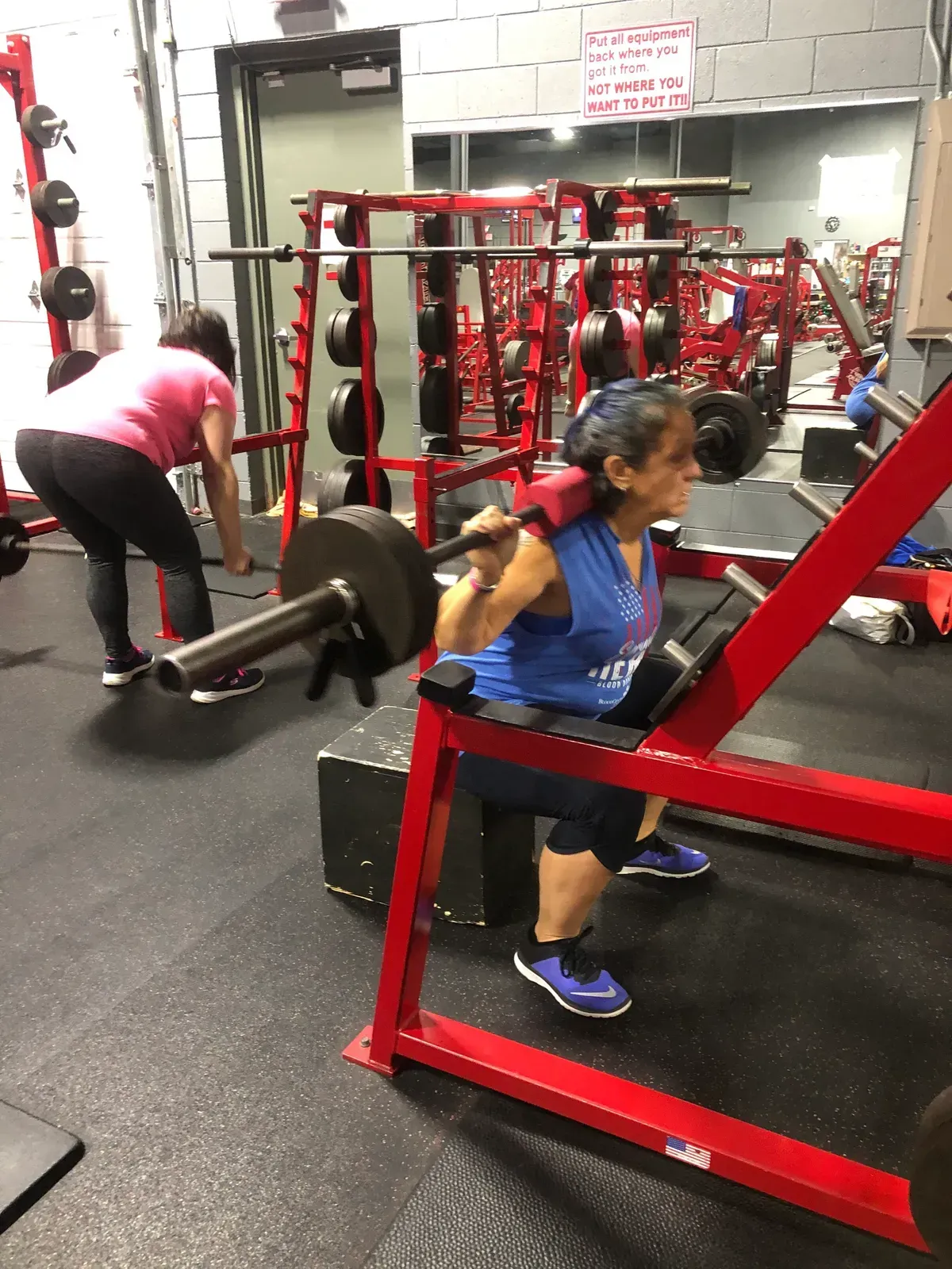 A woman squatting with a barbell in a gym