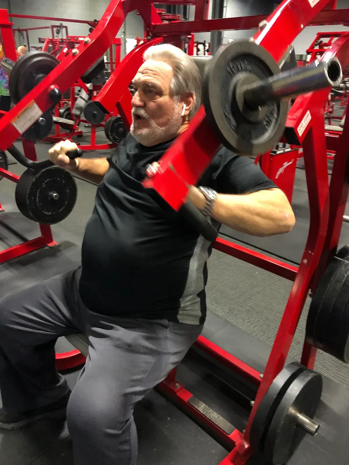 A man is squatting on a machine in a gym