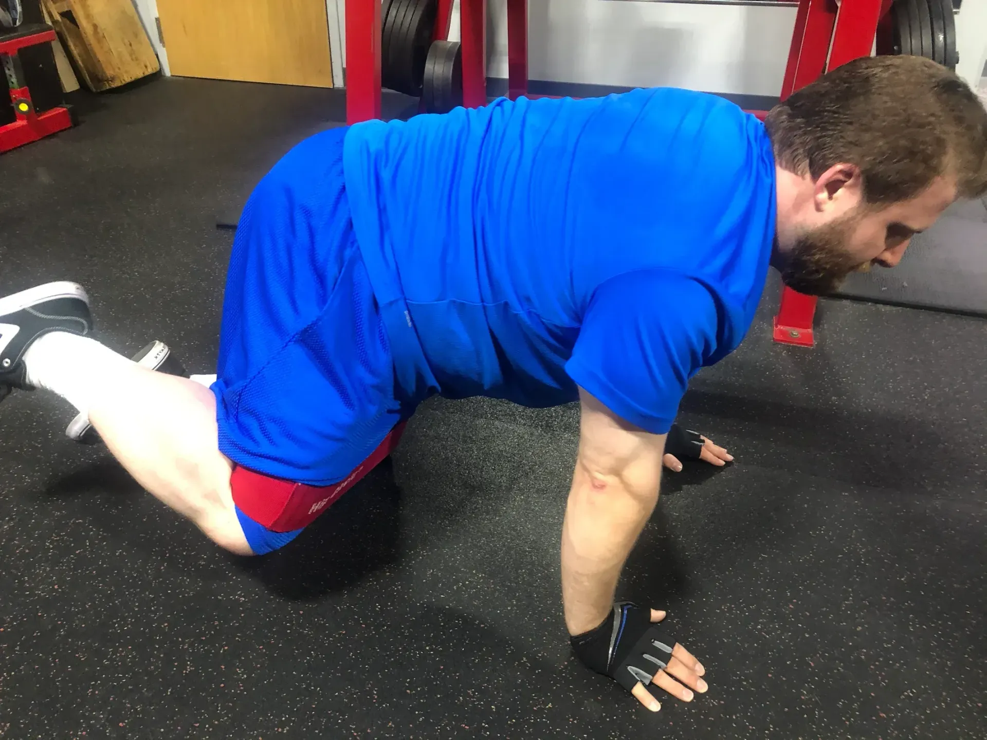 A man is doing push ups on his knees in a gym.