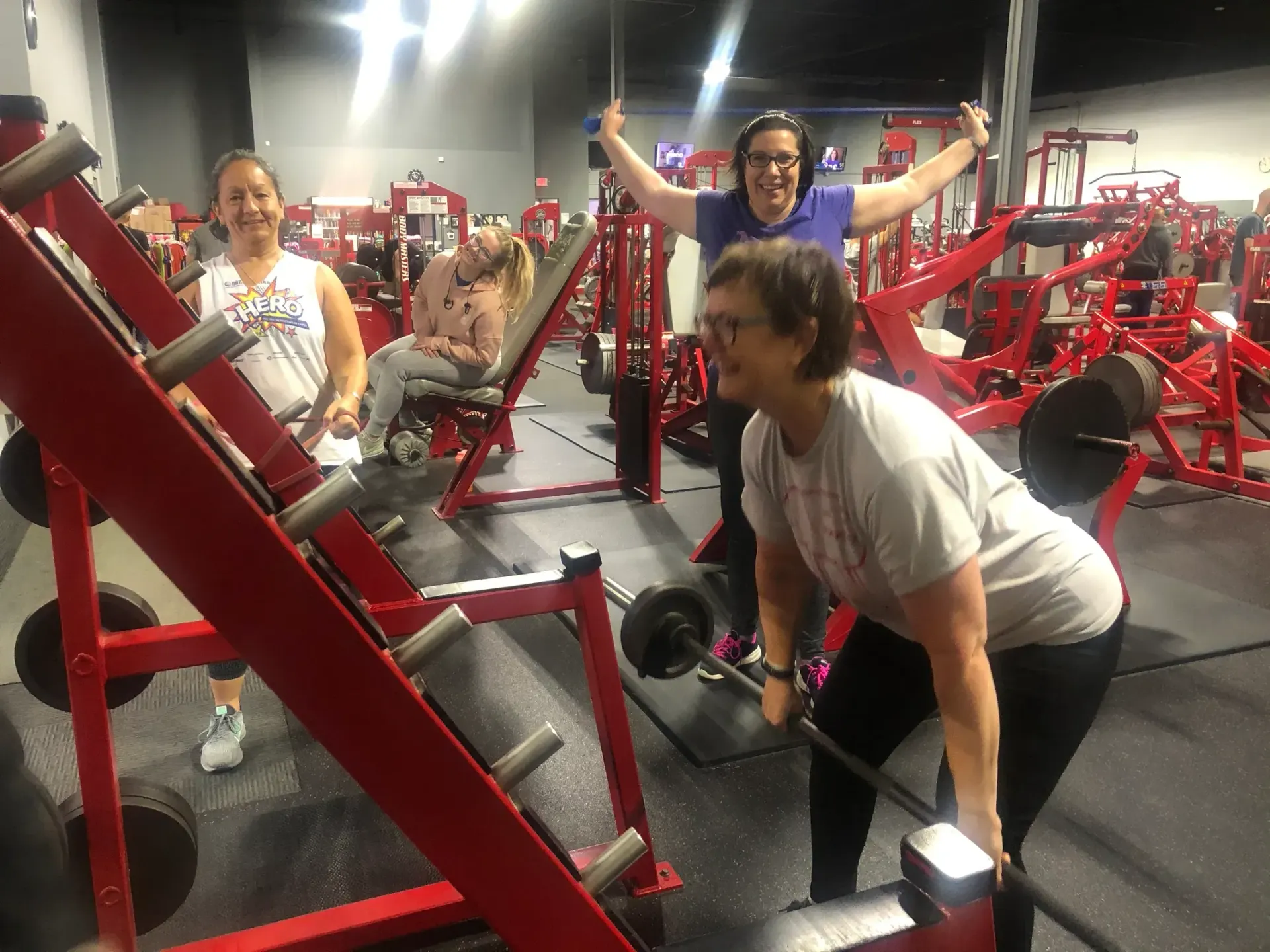 A woman is lifting a barbell in a gym.