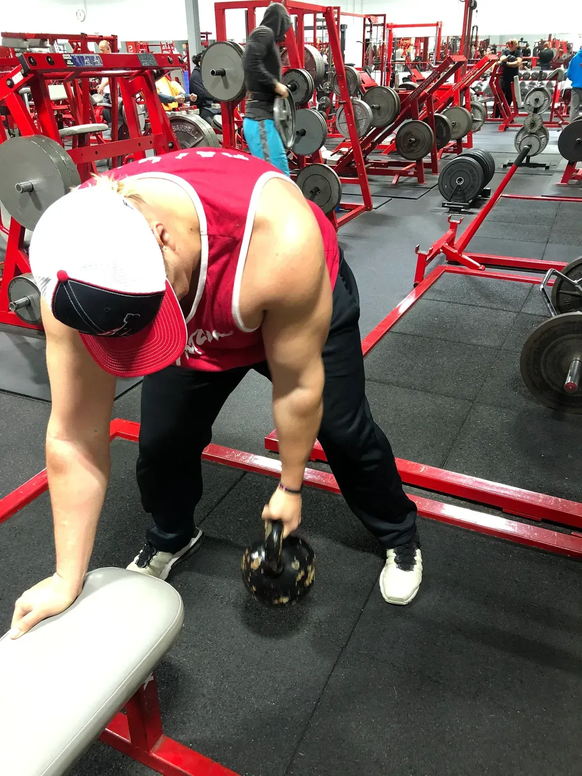 A man is lifting a kettlebell in a gym