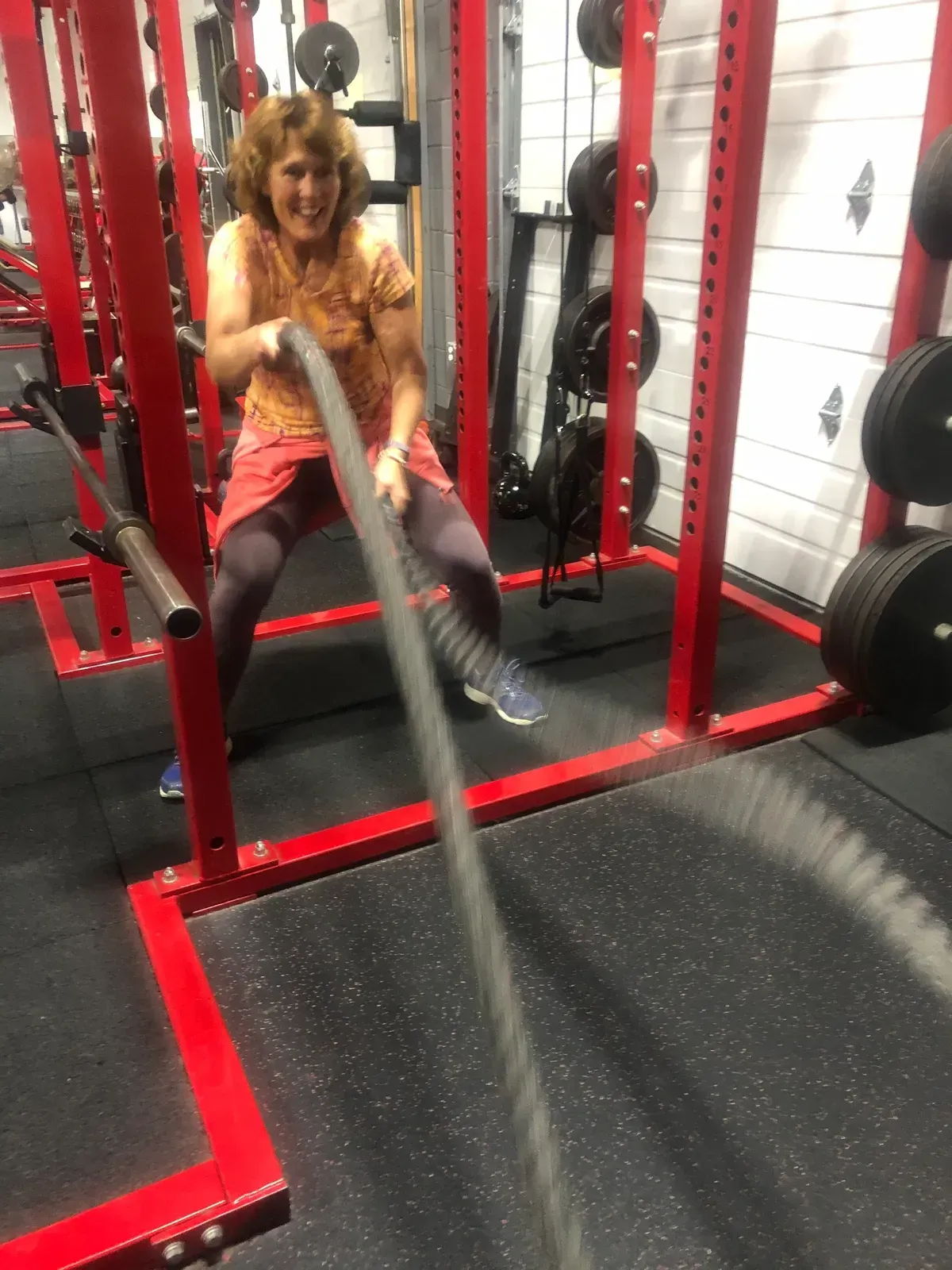 A woman is pulling a rope in a gym.