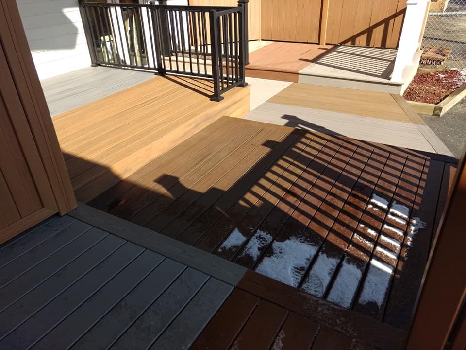 Composite decks with varying colors and a black metal railing on a sunny day.