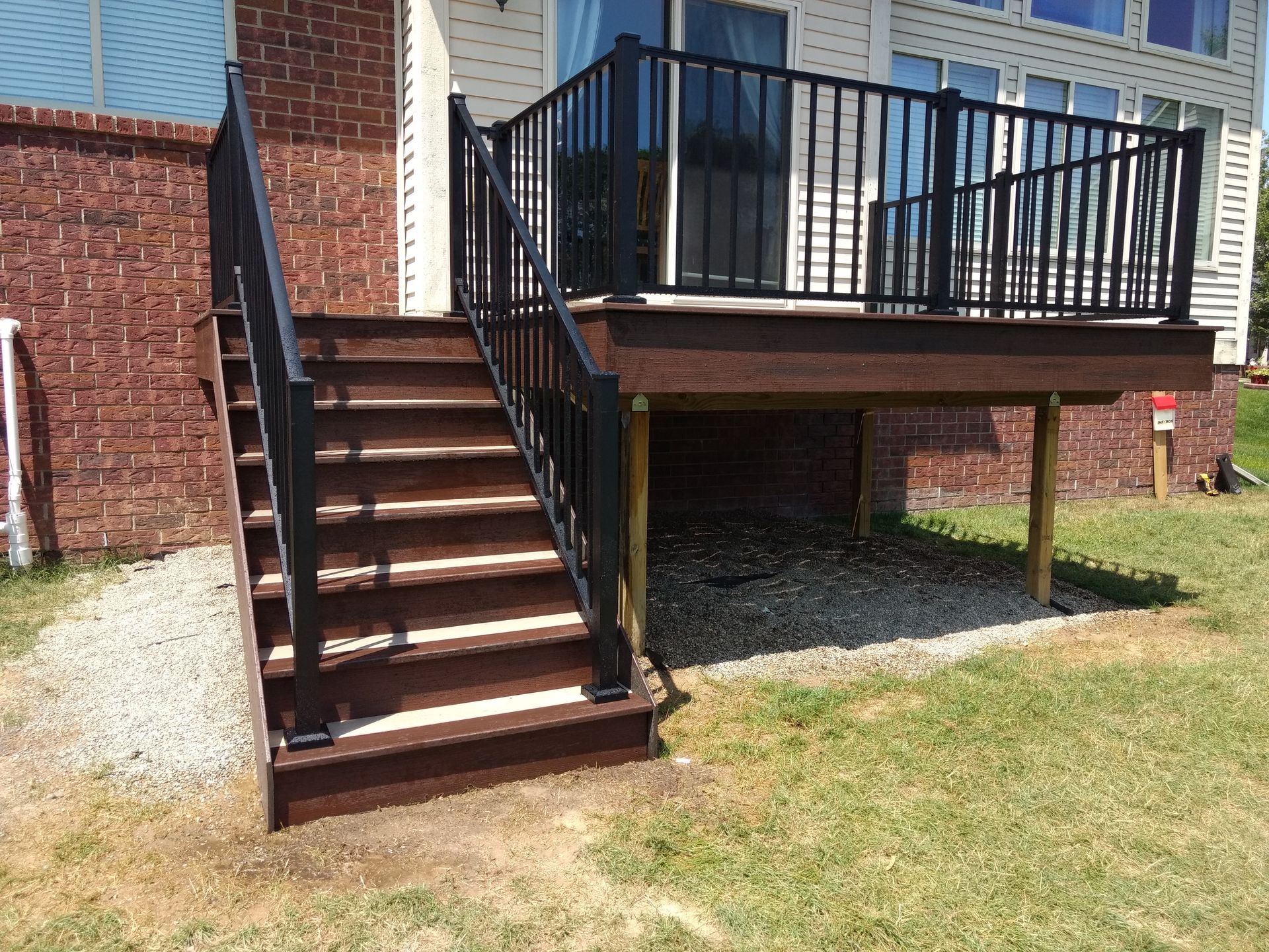 Composite deck with black railing and stairs leading to a backyard.