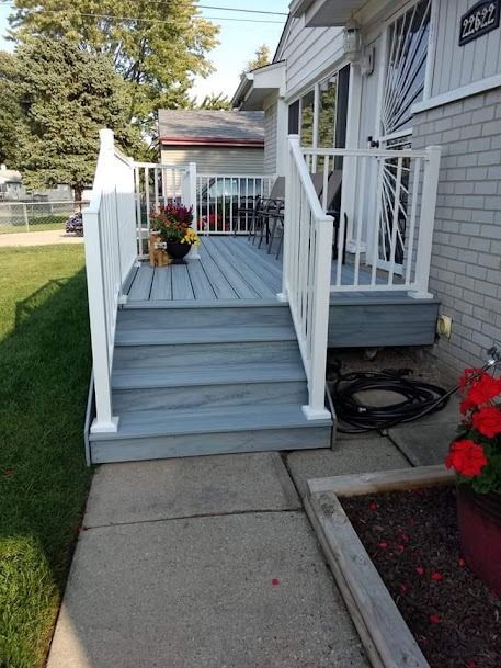 Grey painted deck with white railing and steps, front entrance.