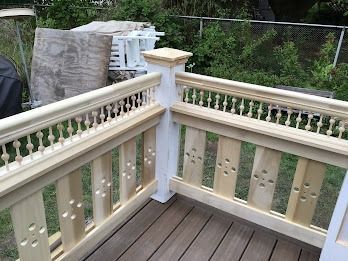 Wooden deck railing with decorative balusters and corner post, outdoors.