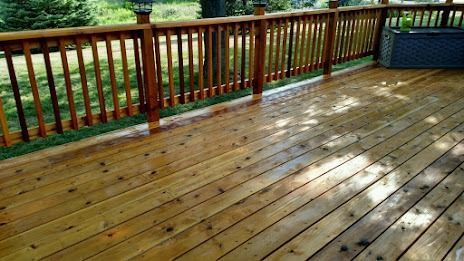 Wooden deck with brown railing, reflecting sunlight.