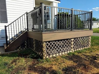 Deck with black railing, brown skirting, and lattice over grassy yard.