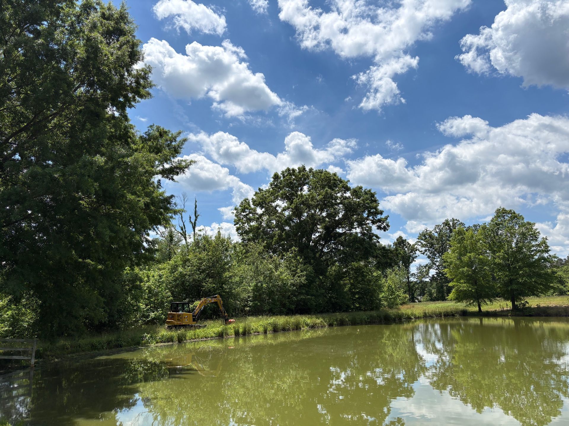 Orange construction vehicle tracks close-up, blurred background of trees and rocks.