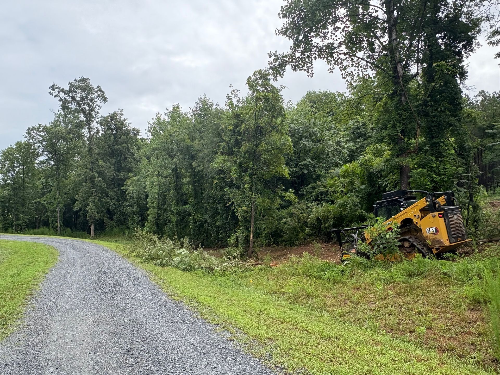 Tan stucco house with a porch, garage, and driveway, set against a green lawn and blue sky.