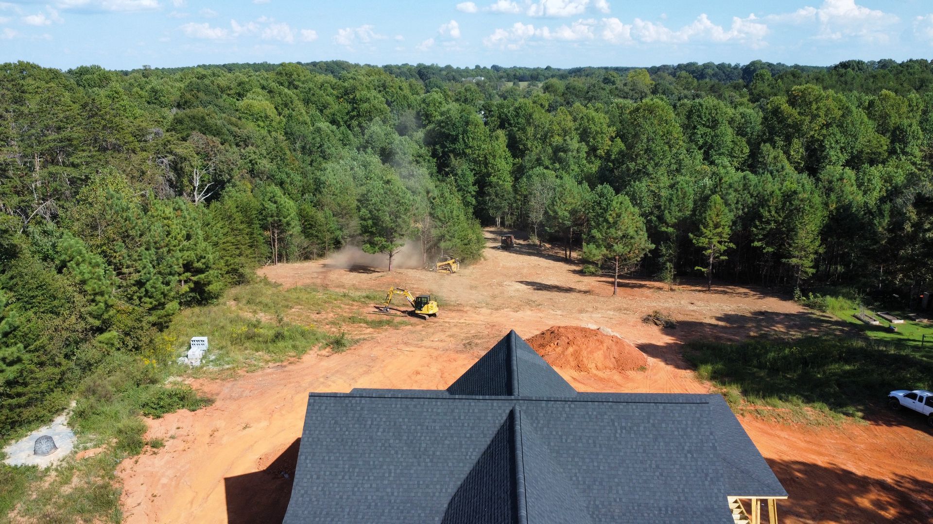Orange construction vehicle tracks close-up, blurred background of trees and rocks.