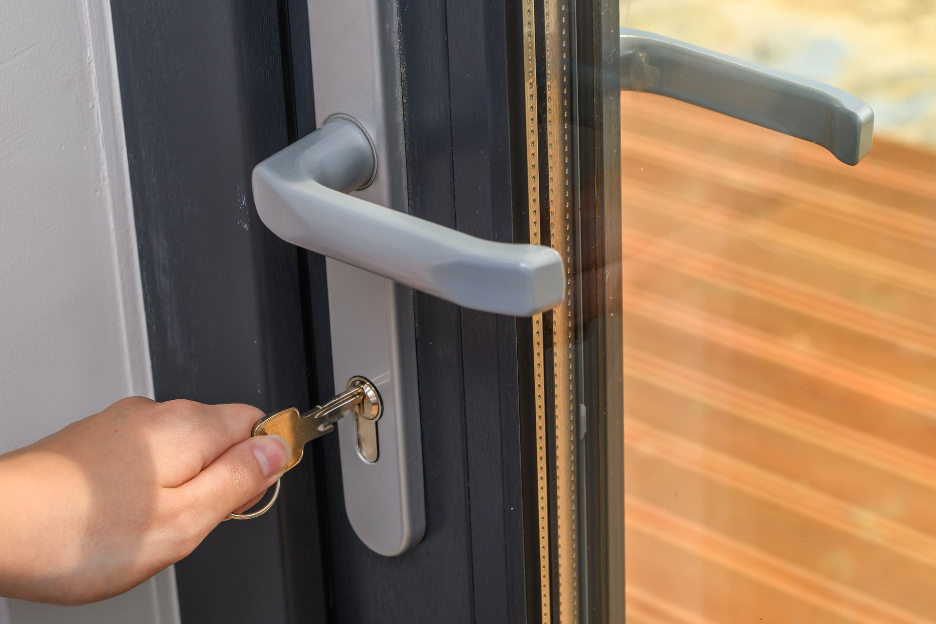 Hand inserting key into a silver door lock on a gray door.