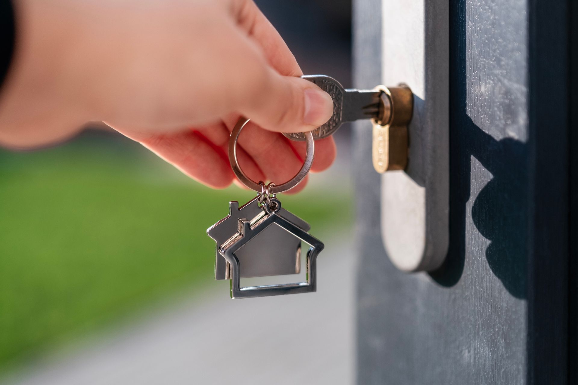 A person is holding a key with a house keychain attached to it. A person is holding a key with a house keychain attached to it.