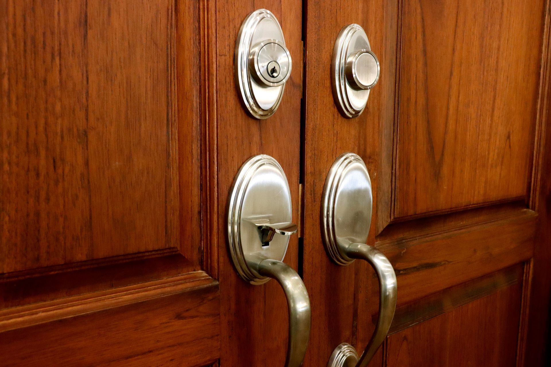 A close up of a wooden door with stainless steel handles and locks.
