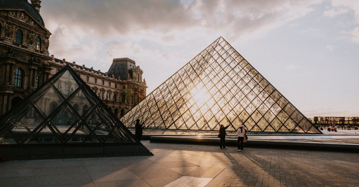 A couple of people standing in front of a pyramid in paris.