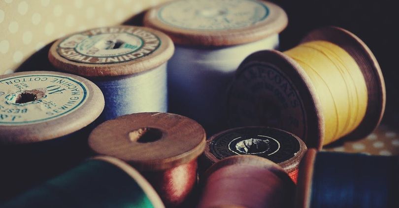 A bunch of spools of thread are sitting on a table.