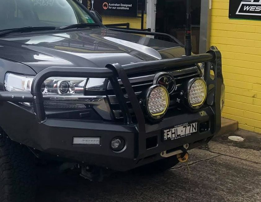 A Black Suv With a Black Bumper is Parked in Front of a Yellow Building — Westlakes 4x4 Centre in Newcastle, NSW