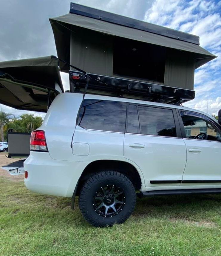 A White Suv With a Tent on Top of It is Parked in the Grass — Westlakes 4x4 Centre in Newcastle, NSW