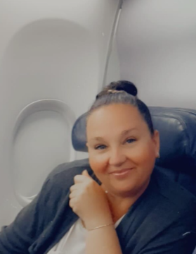 A woman is holding a cup of coffee in front of a cherry blossom tree.