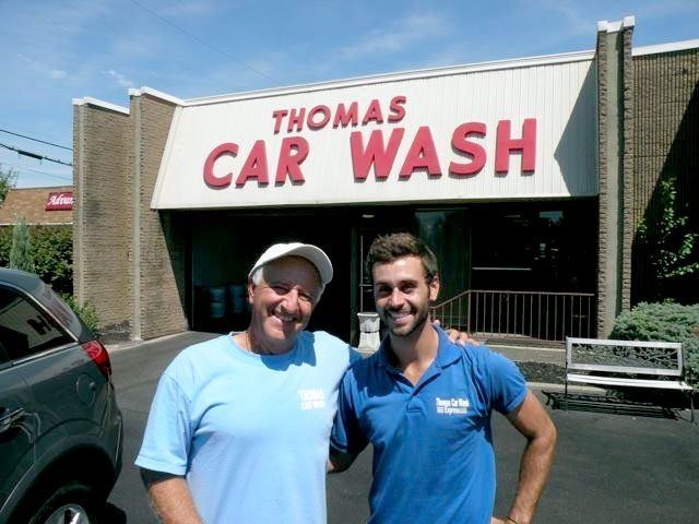 Tom's son Elio and grandson Alex in front of a Thomas Car Wash building.