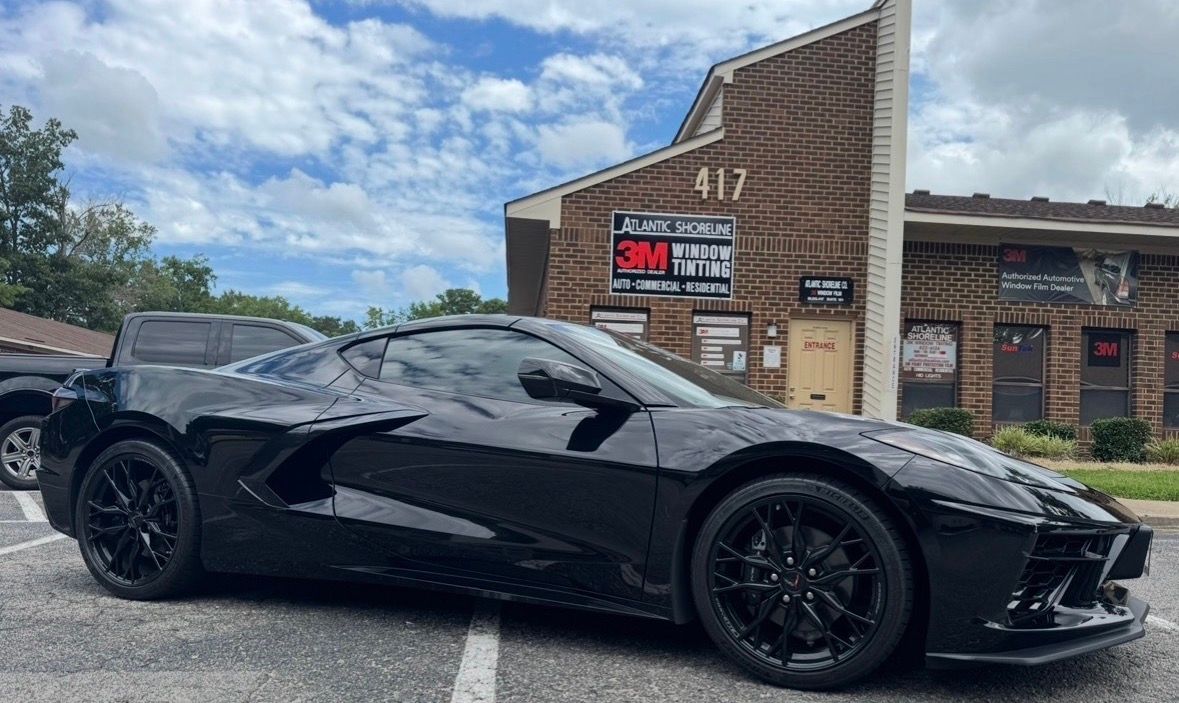 Black Corvette sports car parked in front of a building with a 3M paint protection sign.