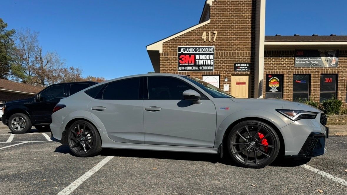 Gray car with tinted windows parked outside a building with tinting services.