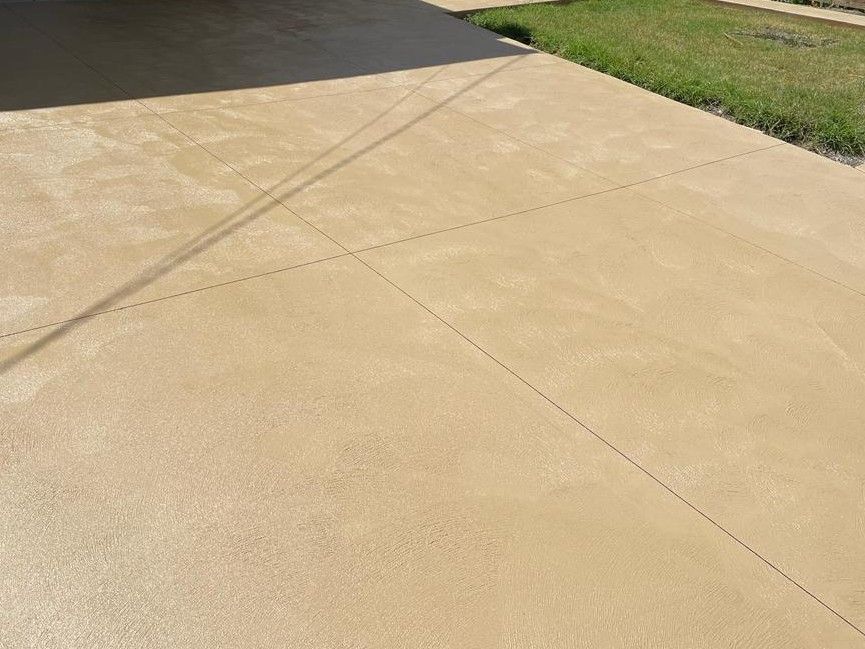 Freshly installed coloured concrete driveway in Frankston, VIC, featuring a warm sandstone finish with a broom texture and control joints on a residential property.