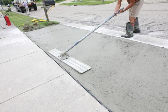 A professional concreter smoothing the concrete surface of a concrete walkway in a residential area in Frankston VIC.