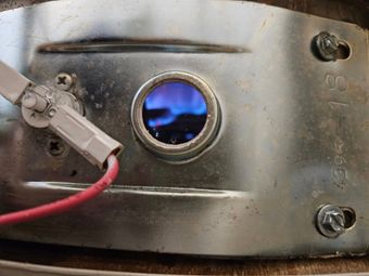 A close up of a metal object with a blue flame coming out of it.