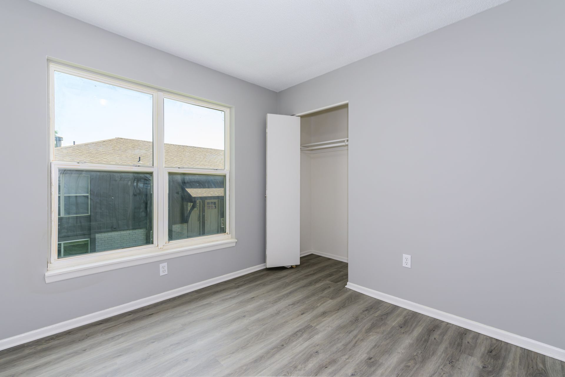 An empty bedroom with a large window and a closet.