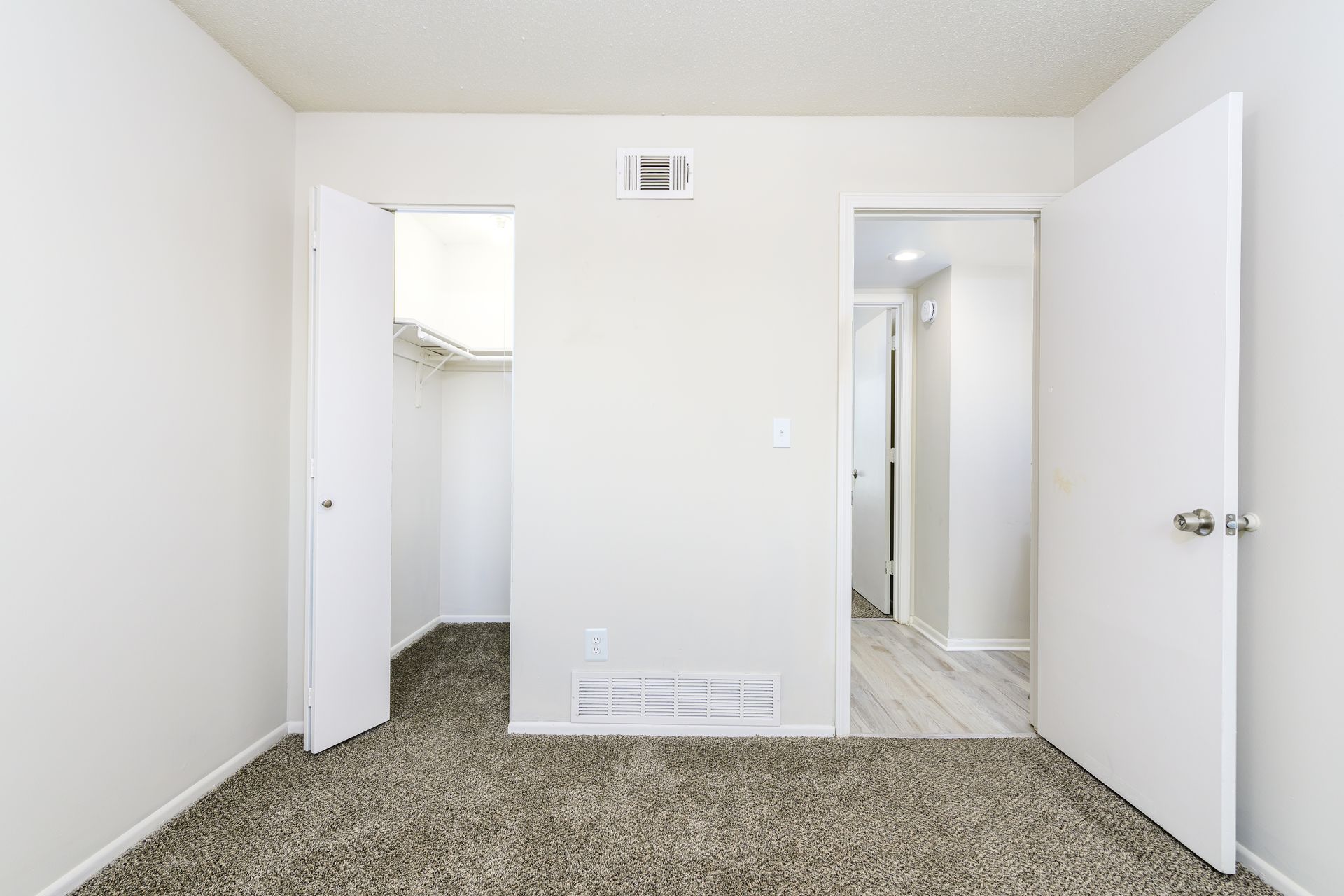 An empty bedroom with a closet and a walk in closet.