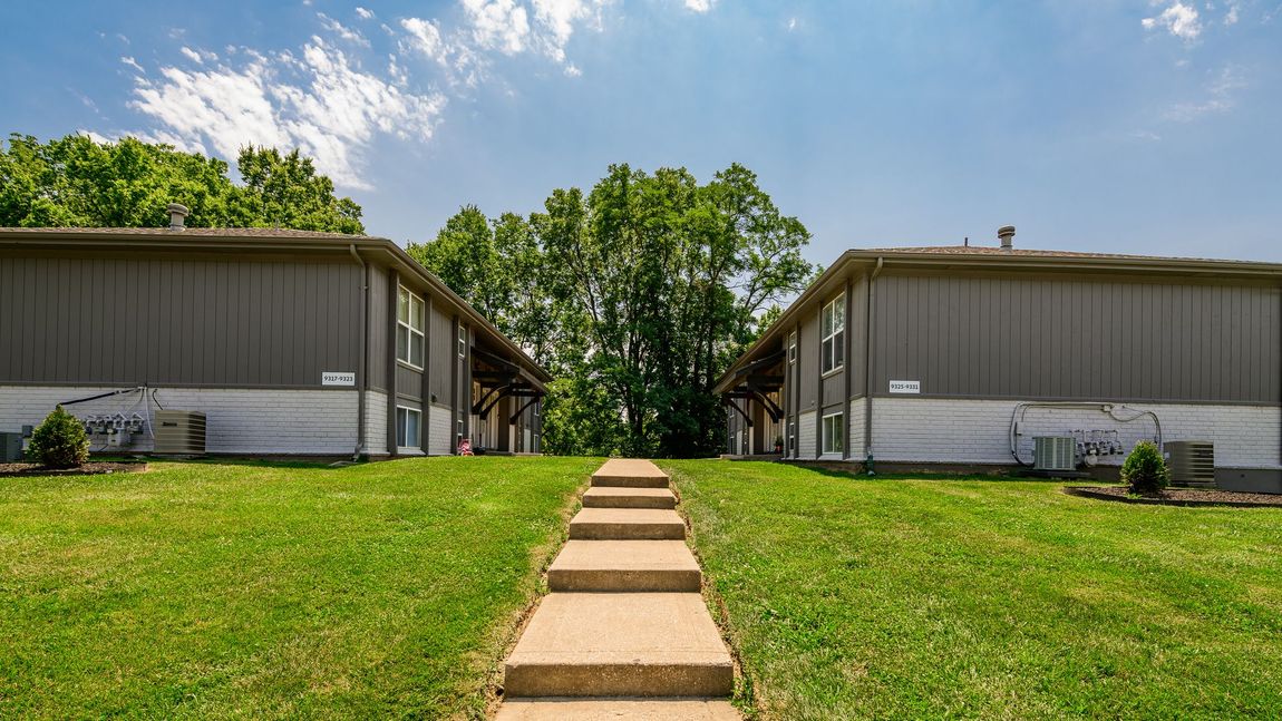 A concrete walkway leading to a row of apartment buildings.