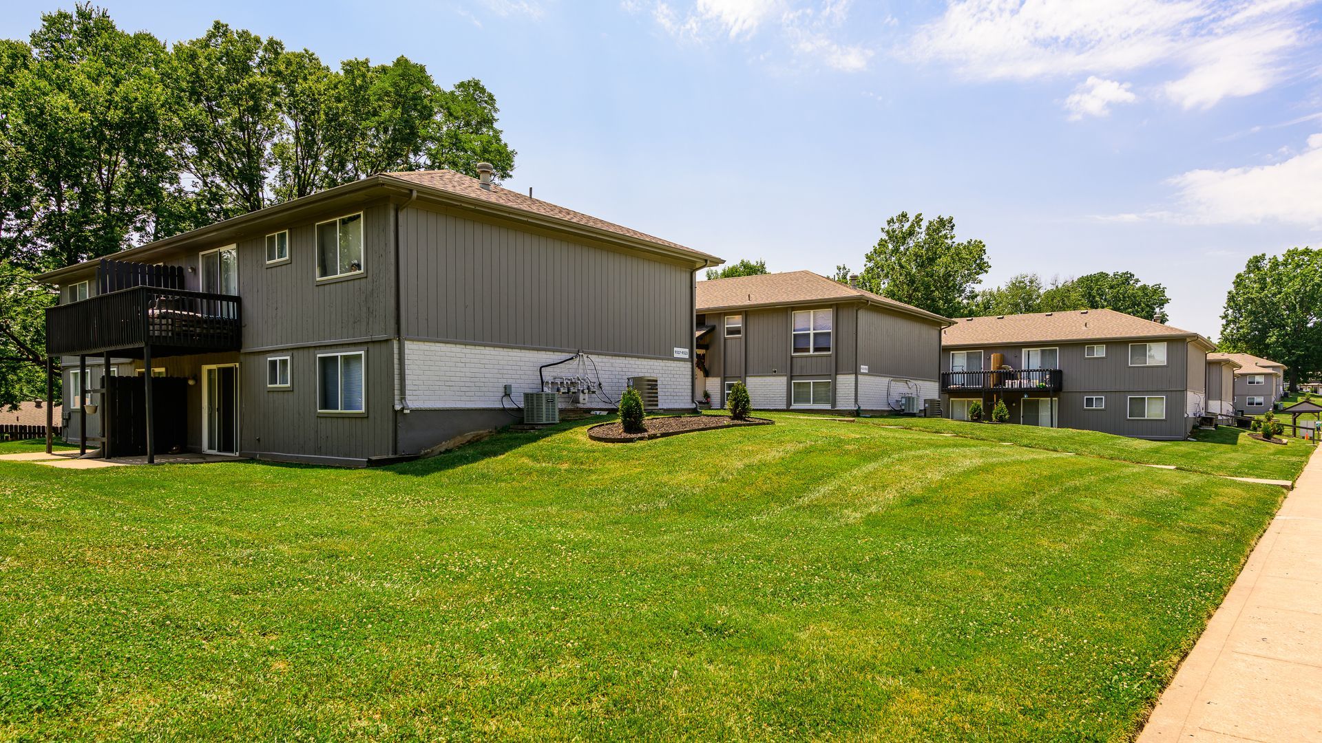 A row of apartment buildings with a lush green lawn in front of them.