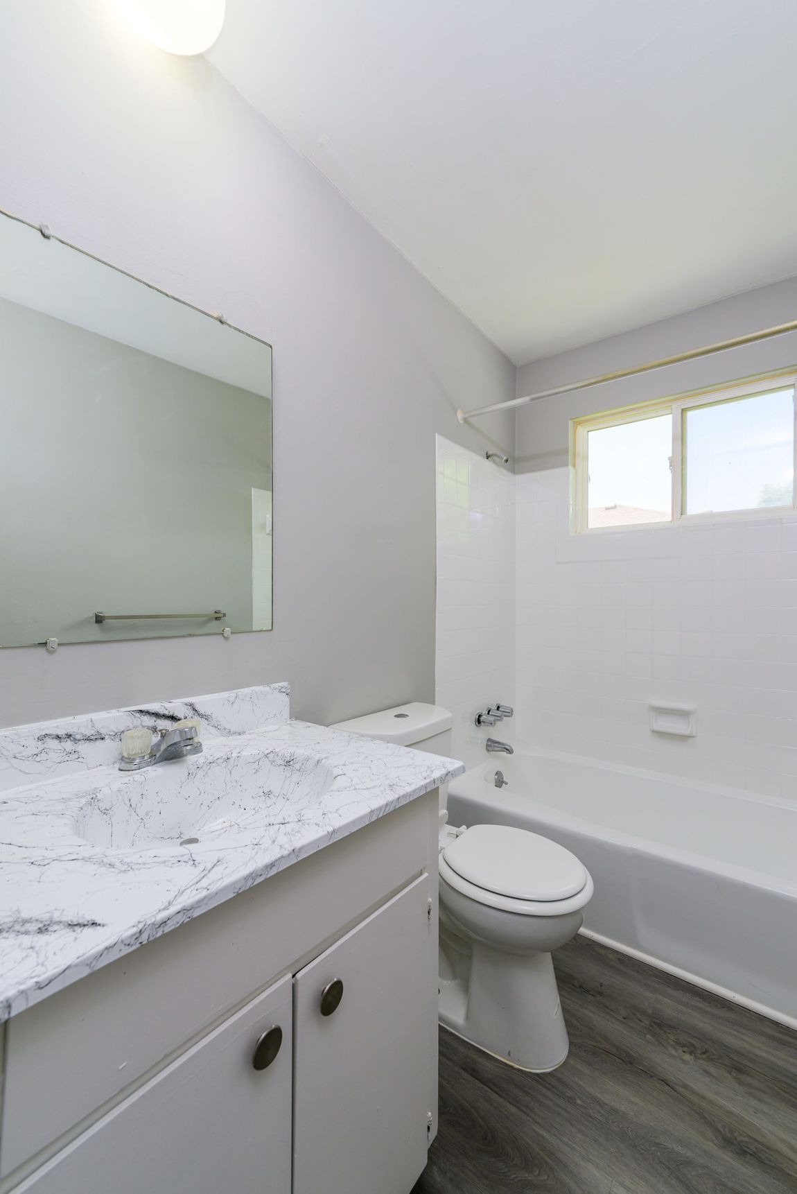 A bathroom with a toilet , sink , tub and mirror.