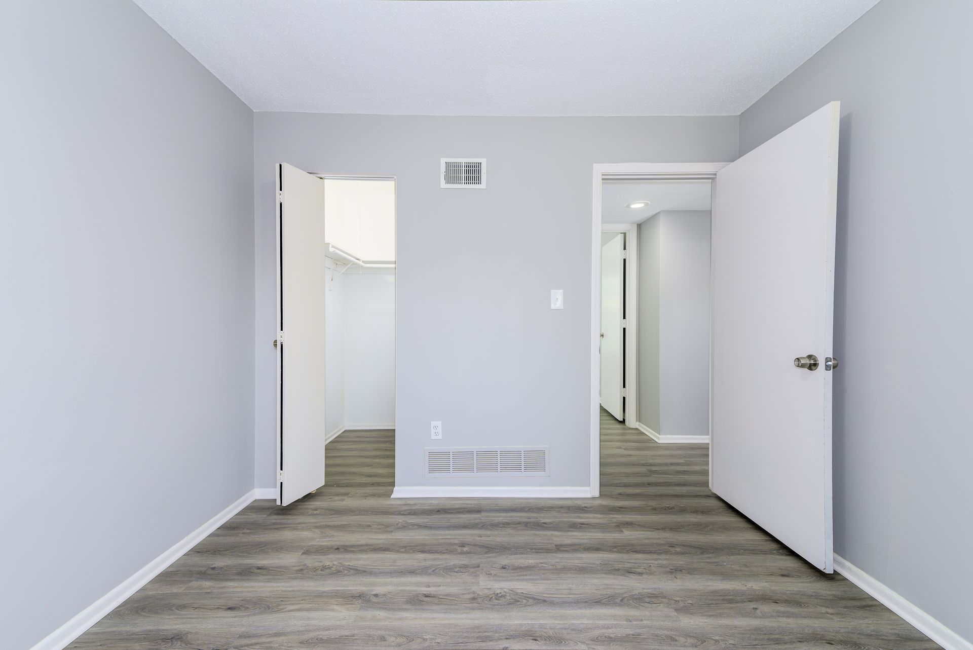 An empty room with a wooden floor and white walls.