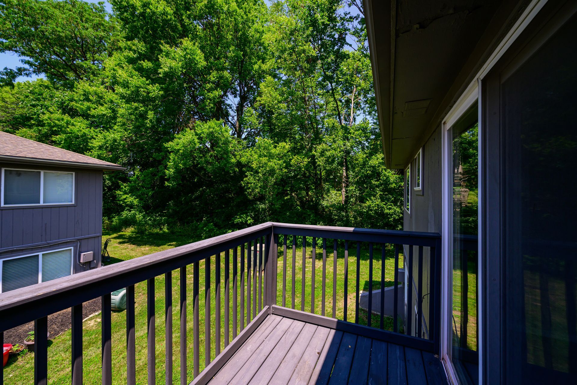 A balcony with a sliding glass door and trees in the background