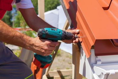 A man is installing a metal roof with easy drainage on a building site.