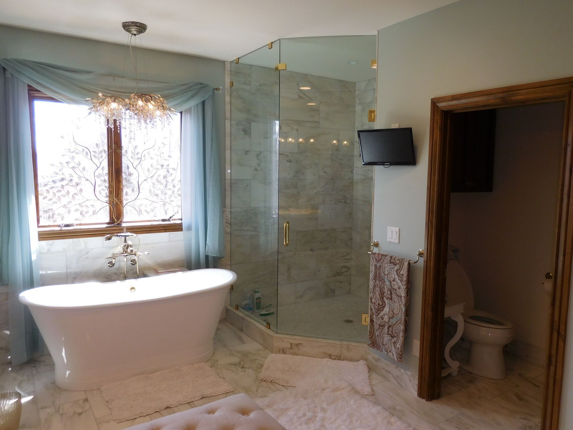 A bathroom with a tub and a television on the wall