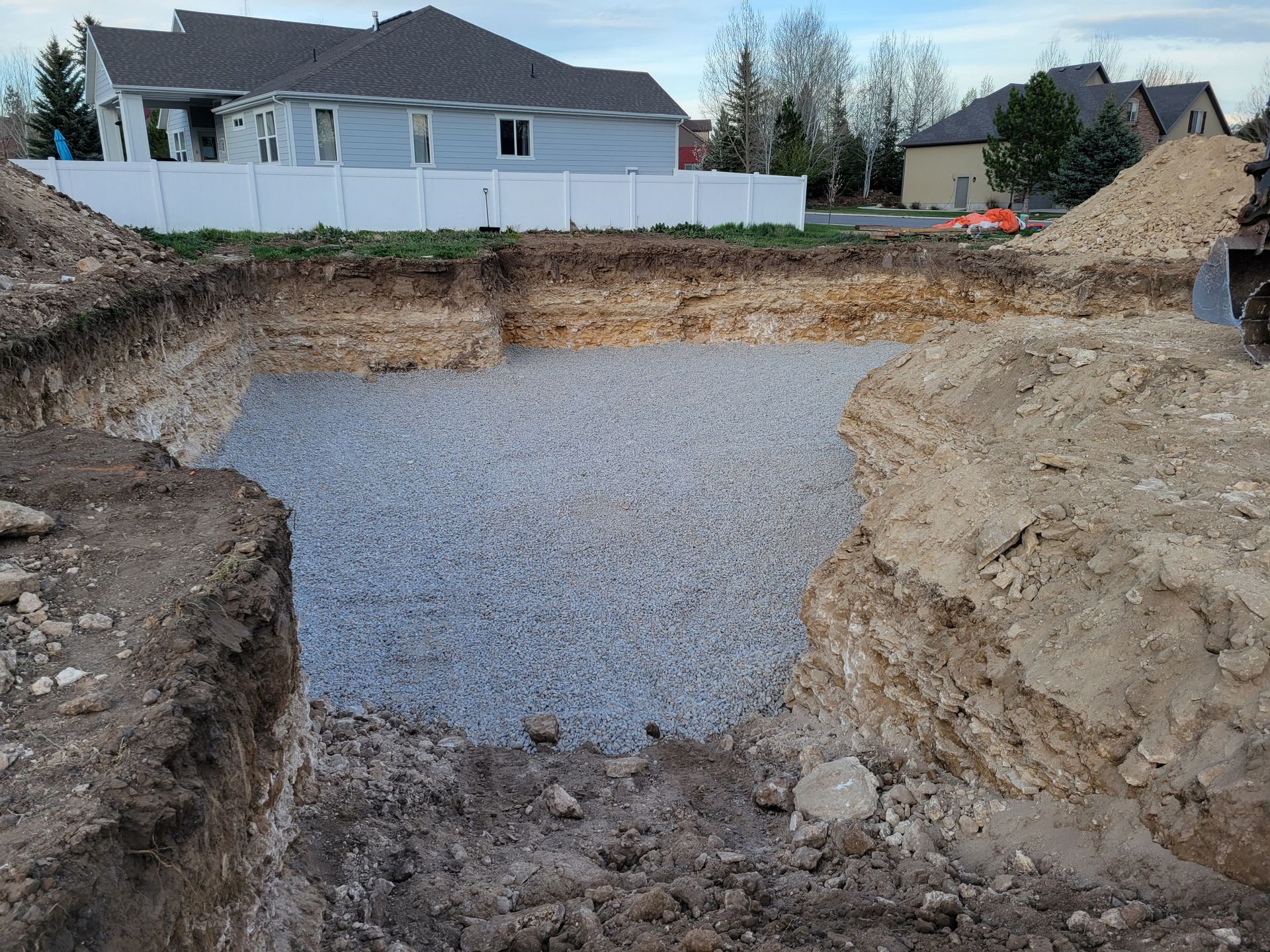 A large hole in the ground with a house in the background.