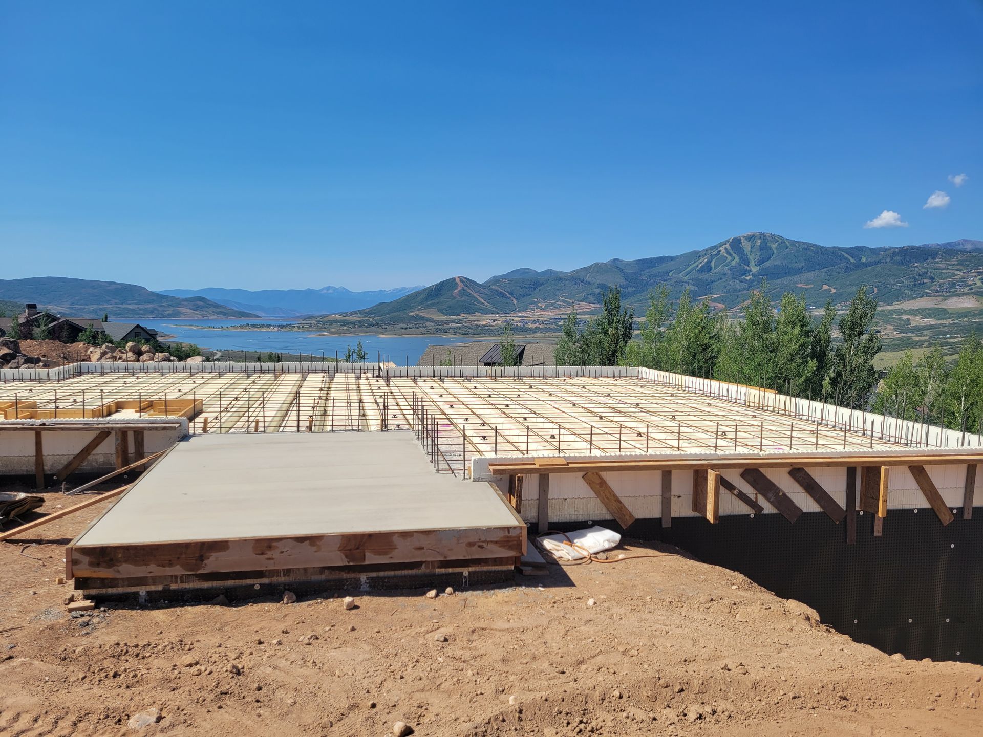 A building under construction with a view of a lake and mountains in the background.