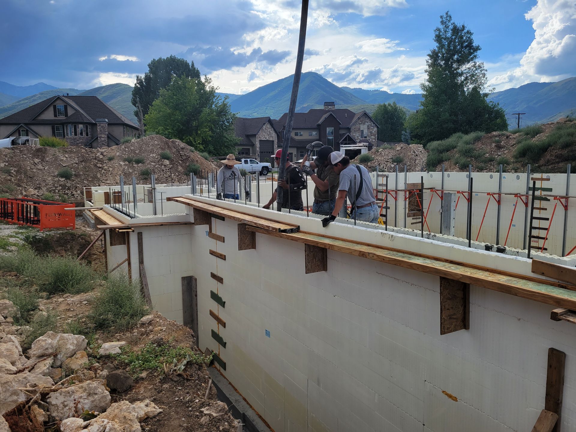 A group of construction workers are working on a building with mountains in the background.