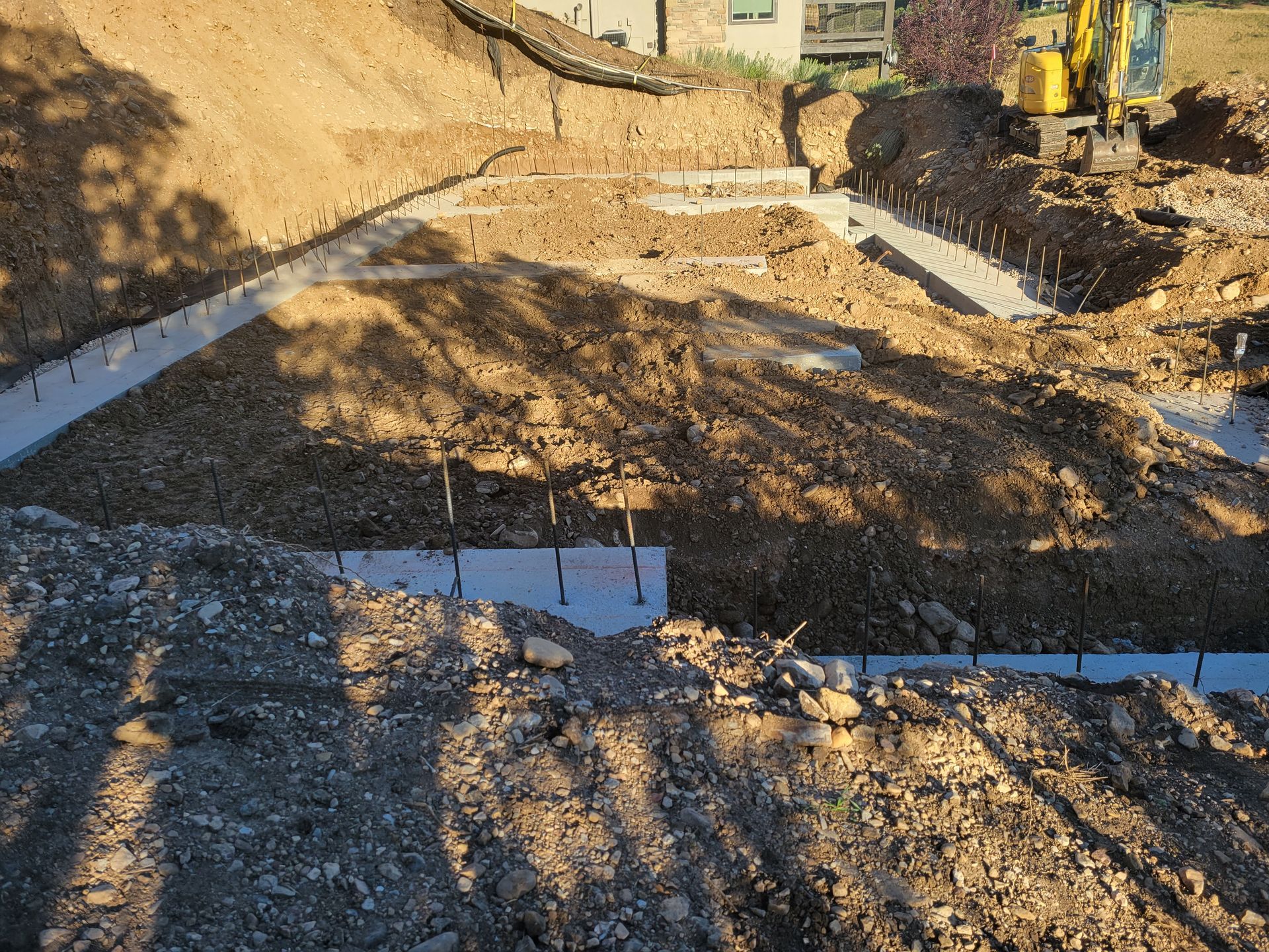 A construction site with a yellow excavator in the background.