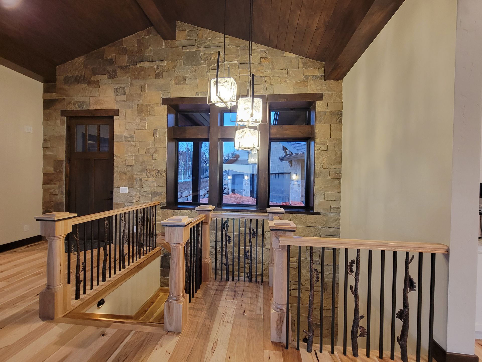 A staircase in a house with a wooden railing and a stone wall.