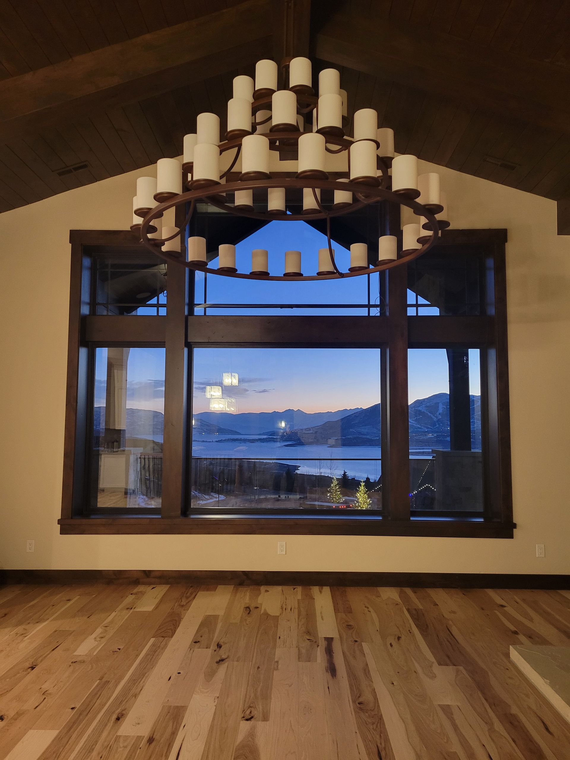 An empty room with a large window and a chandelier hanging from the ceiling