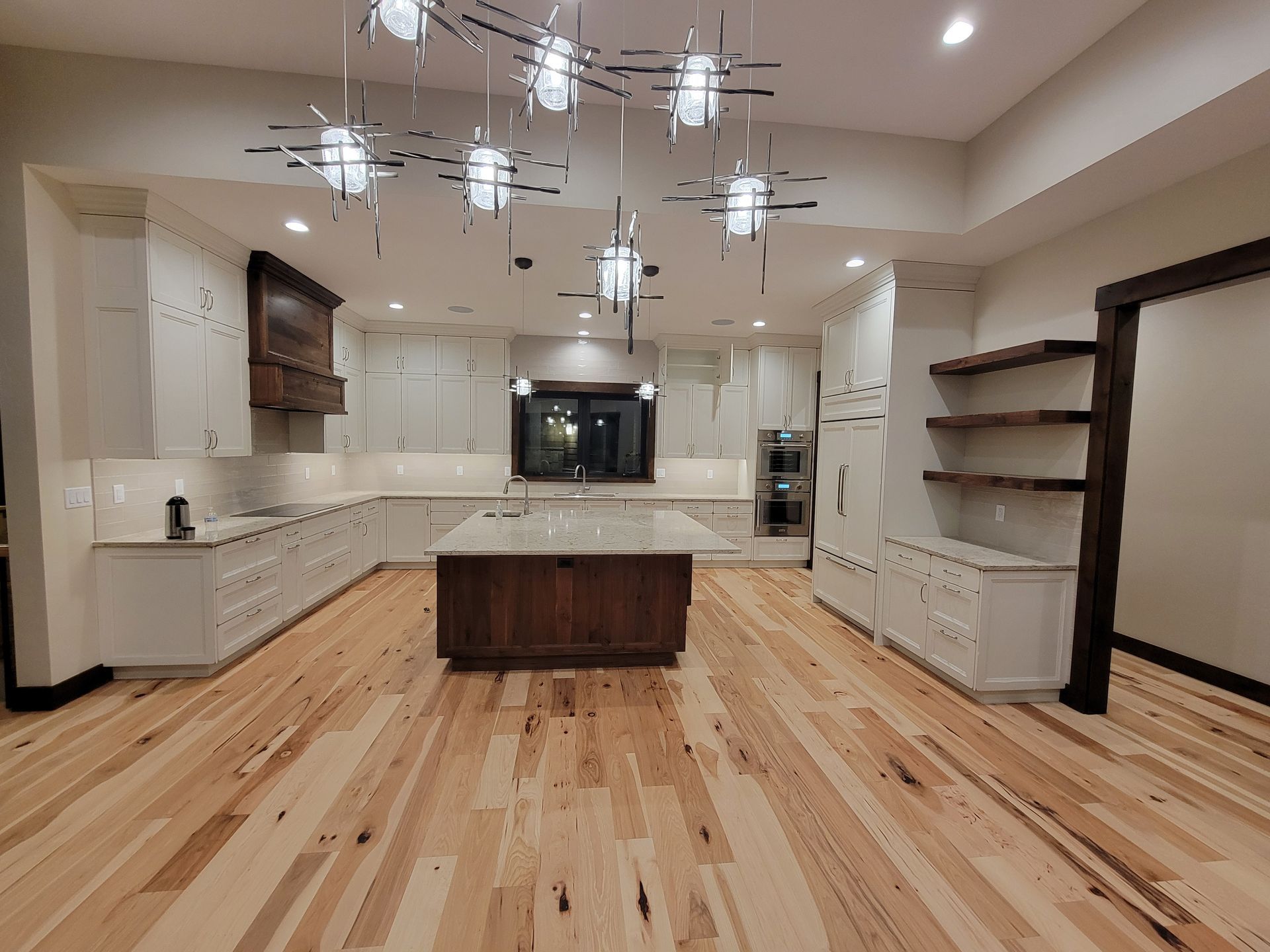 A large kitchen with hardwood floors and white cabinets