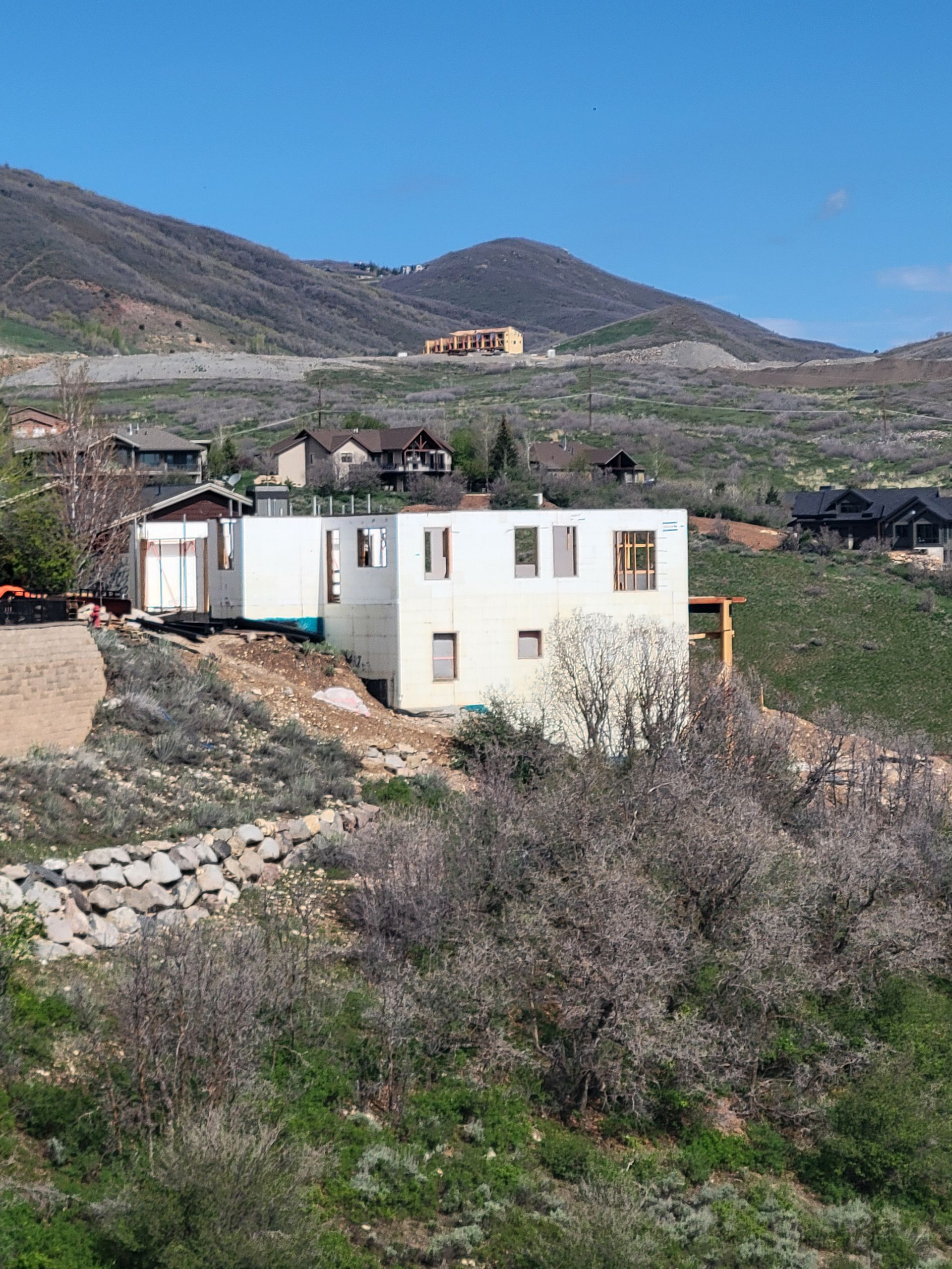A white house is sitting on top of a hill with mountains in the background.