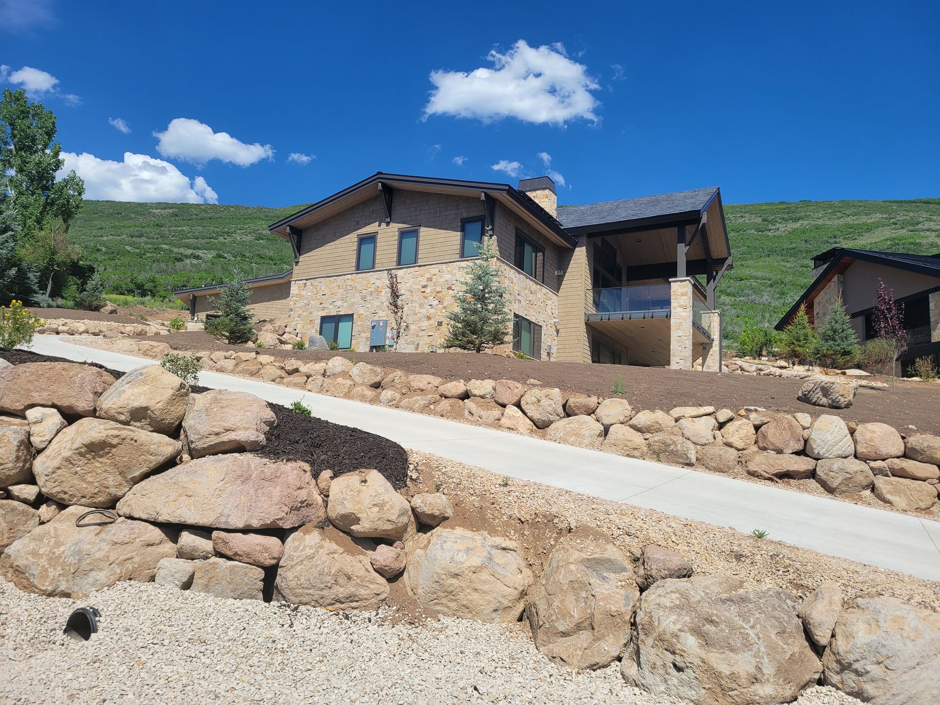 A large house is sitting on top of a hill next to a stone wall.