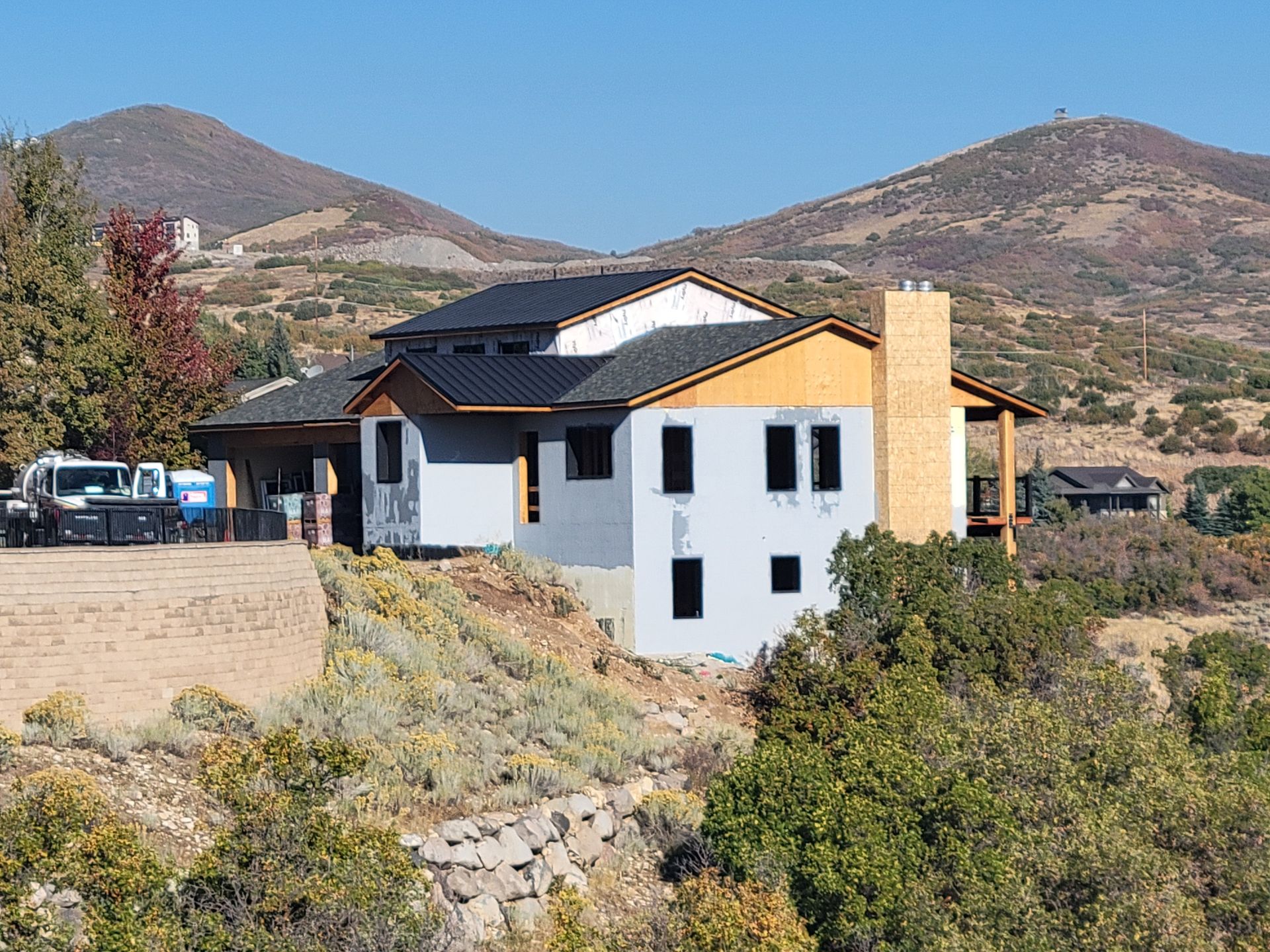 A house is being built on a hill with mountains in the background