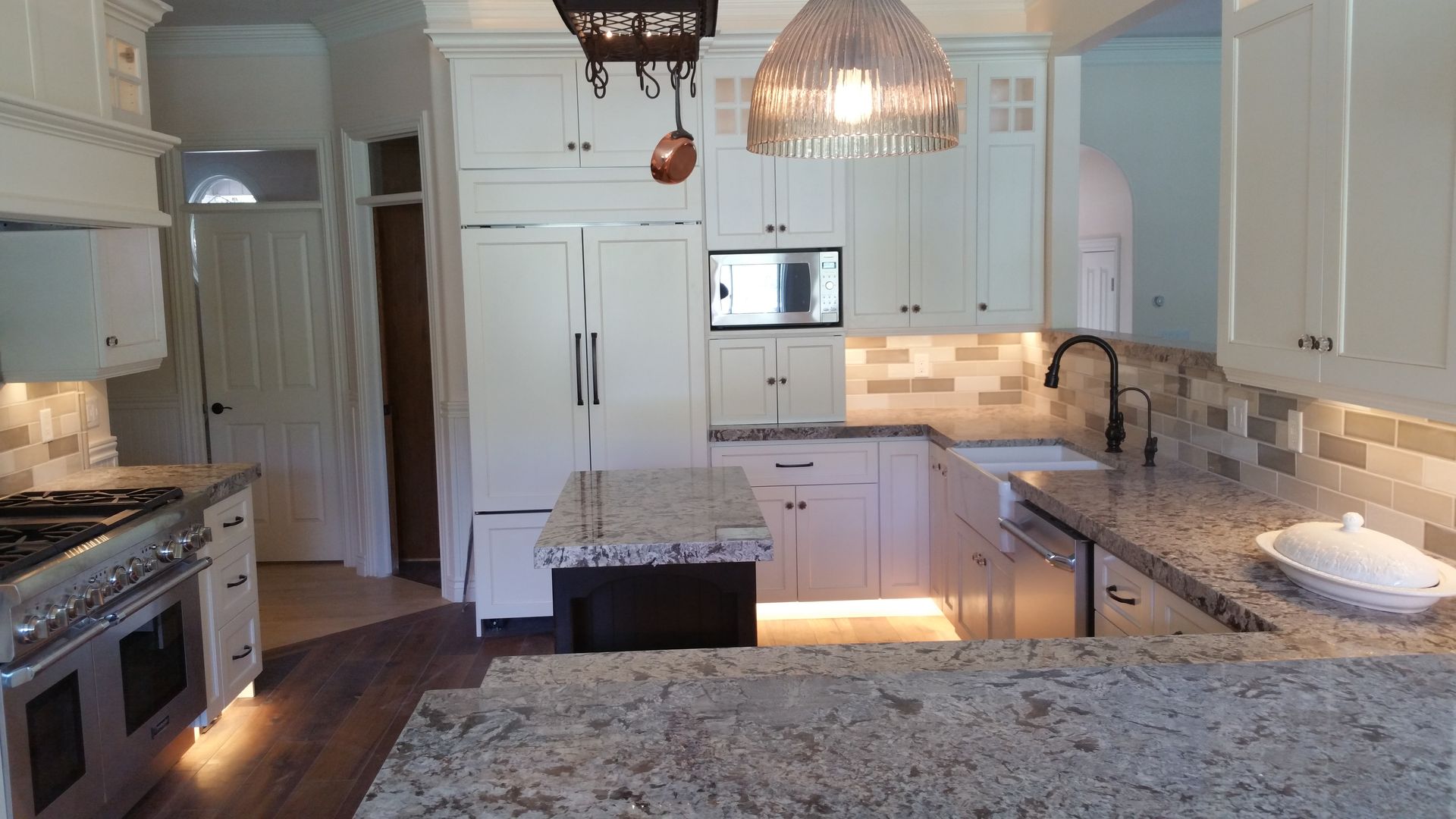 A kitchen with white cabinets and granite counter tops.