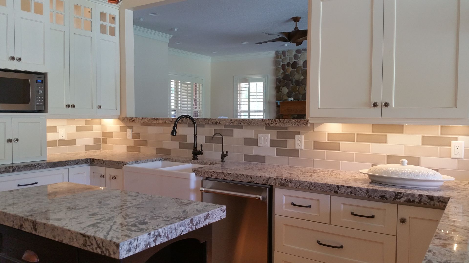 A kitchen with white cabinets , granite counter tops , stainless steel appliances and a sink.